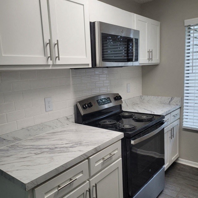 Apartments in Marietta, GA for Rent - Arlington Park - Modern Kitchen with Stainless Steel Oven and Microwave, White Cabinetry, Marble Counter, Window, and Grey Walls