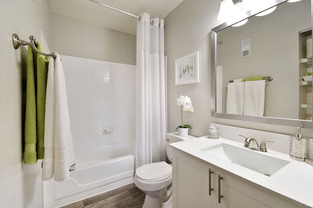 a bathroom with a white toilet next to a white bathtub and a white sink with a