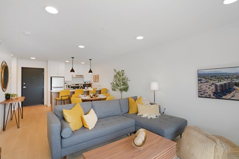 A living room with a grey couch and yellow pillows.