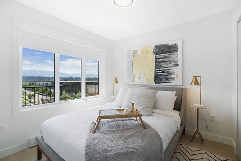 A bedroom with a large bed, a lamp, and a painting on the wall.