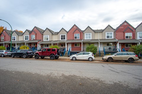 A row of houses with cars parked in front.