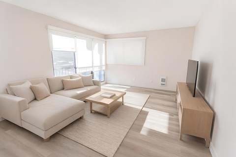 A living room with a white couch, a wooden coffee table, and a flat screen TV.