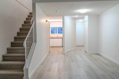 A long hallway with a staircase on the left and a door on the right.