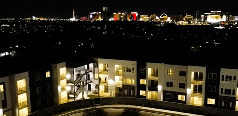 A cityscape at night with a building in the foreground.