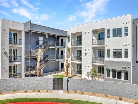 A modern apartment complex with a courtyard and palm trees.
