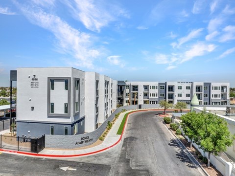 A street view of a residential area with apartment buildings and a clear sky.