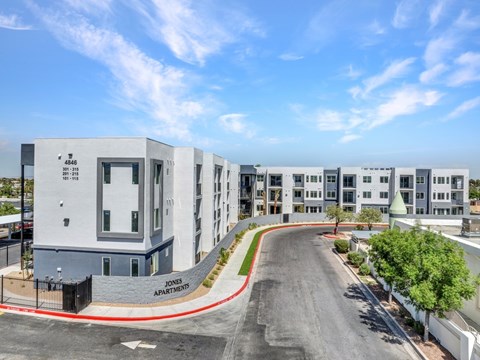 A modern apartment complex named JONE Apartments is shown with a clear blue sky above.