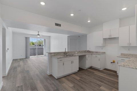 A spacious kitchen with white cabinets and a marble countertop.
