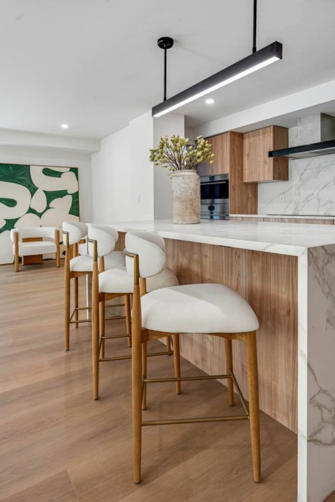 A kitchen with a white counter and wooden chairs.