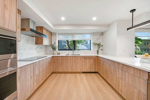 A modern kitchen with wooden cabinets and a marble countertop.