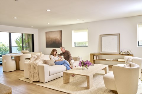 A man and woman are sitting on a couch in a modern living room.