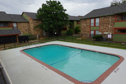 A small pool in a backyard surrounded by a black fence.