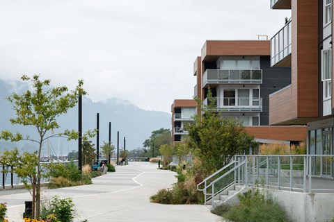 A long concrete walkway leads to a building with a balcony.
