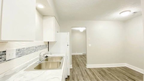 A kitchen with white cabinets and a stainless steel sink.