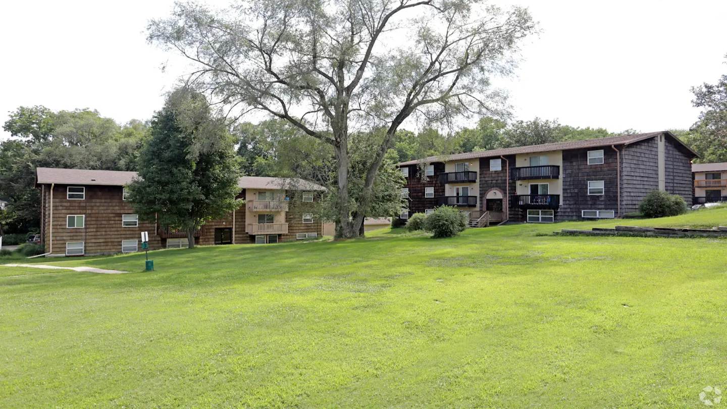 A grassy field with apartment buildings in the background.