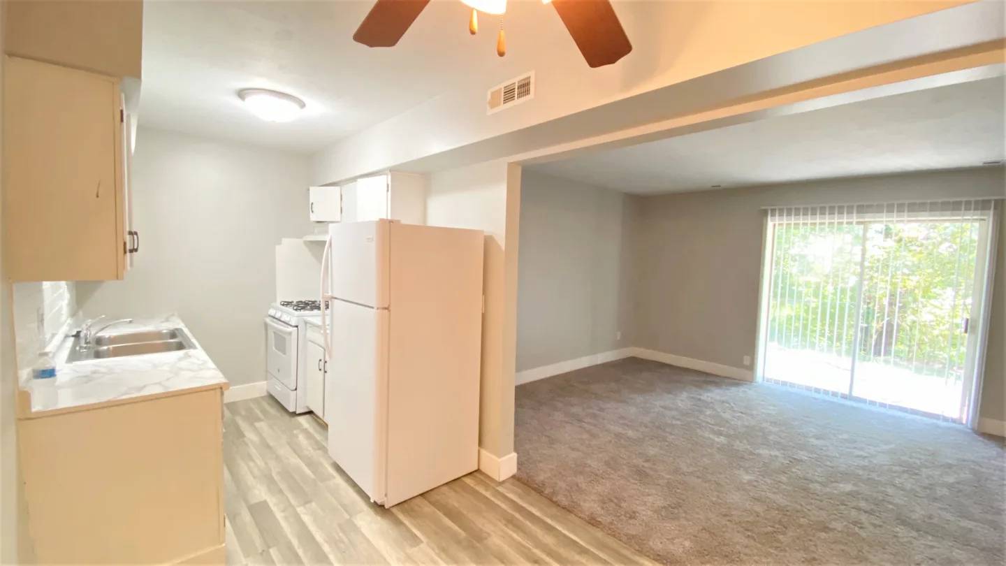 A kitchen area with a refrigerator, sink, and cabinets.