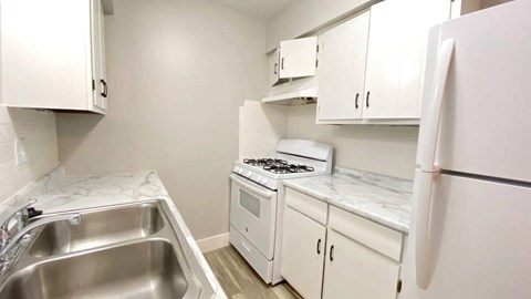 A kitchen with white cabinets and a stove top oven.