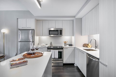 A modern kitchen with white cabinets and stainless steel appliances.
