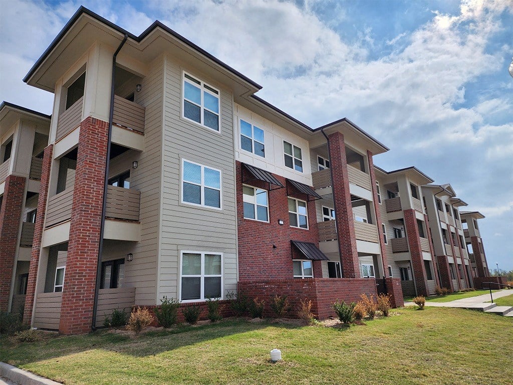 a row of apartment buildings with a grassy yard