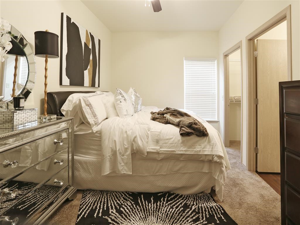 A bedroom with a white bed and a black and white rug.