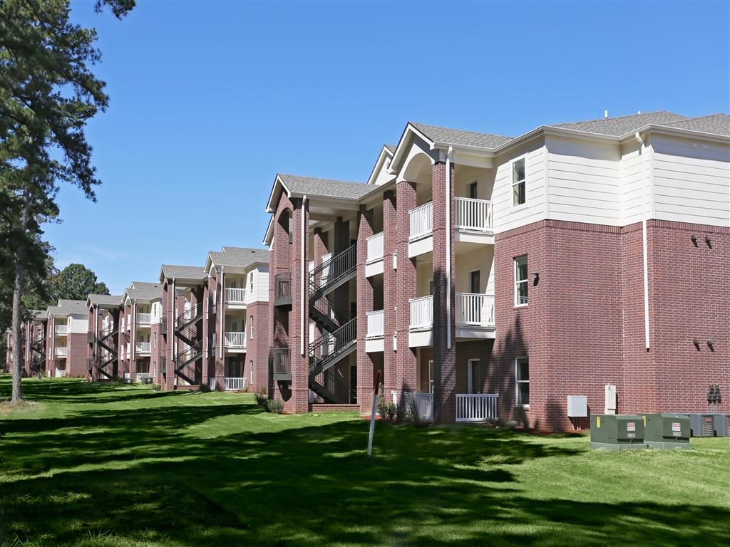 Apartment complex with red brick buildings and green lawns.