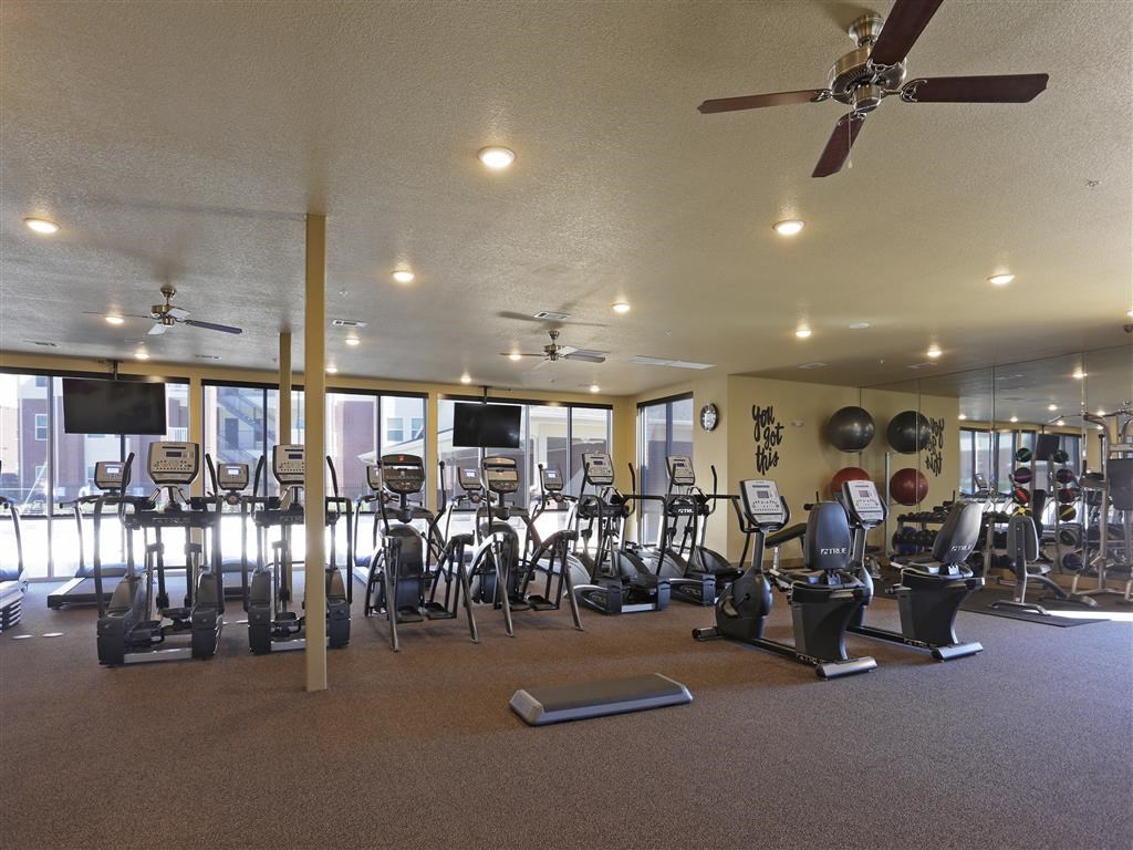 A gym with a variety of exercise equipment including treadmills, stationary bikes, and weight machines.