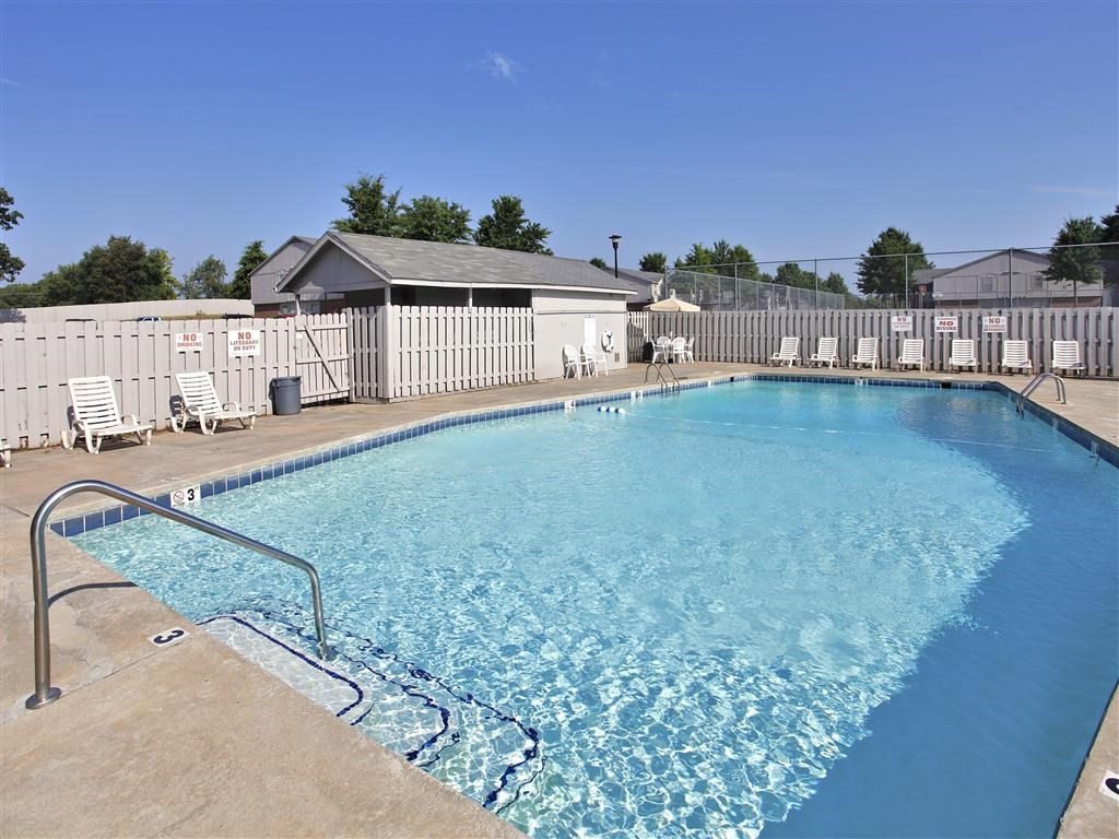 A large swimming pool with a diving board and lounge chairs.