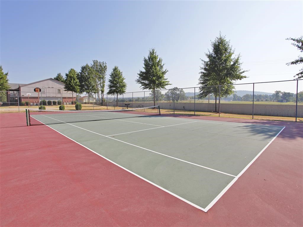 A tennis court with a red surface and white lines.