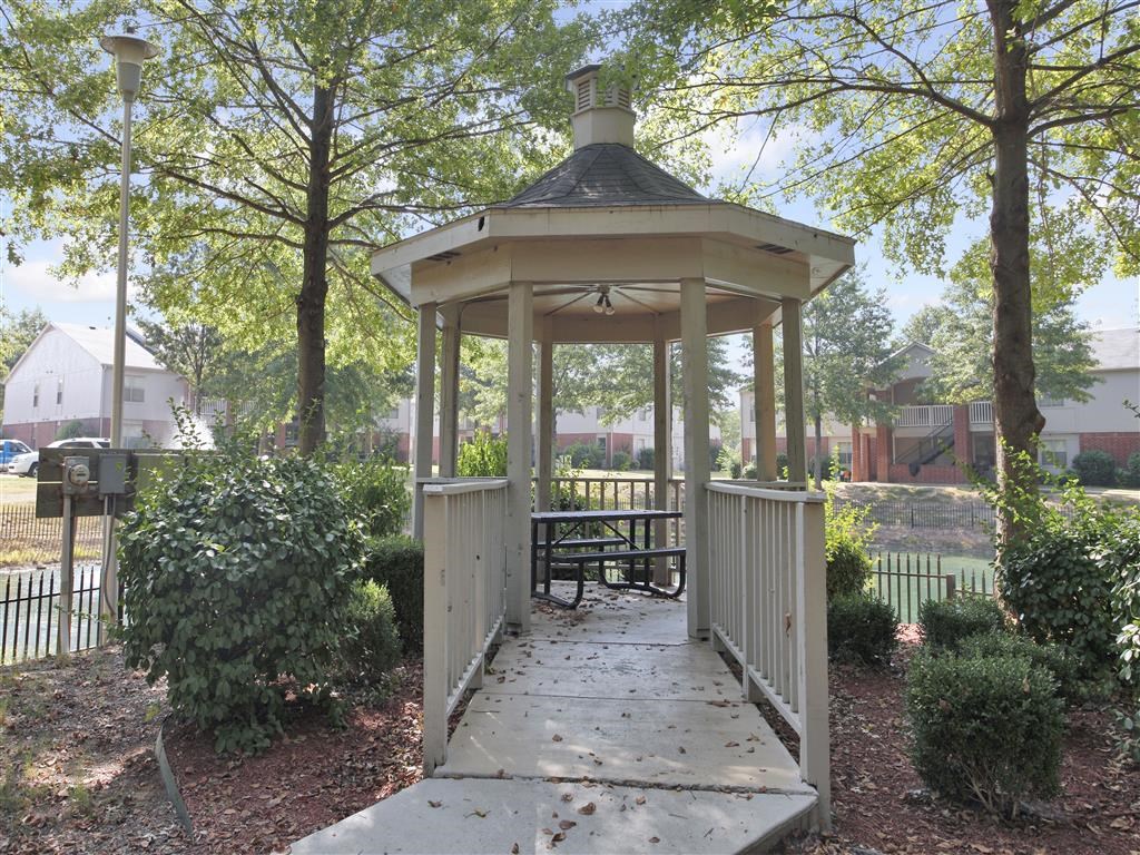 A gazebo with a picnic table is surrounded by trees.