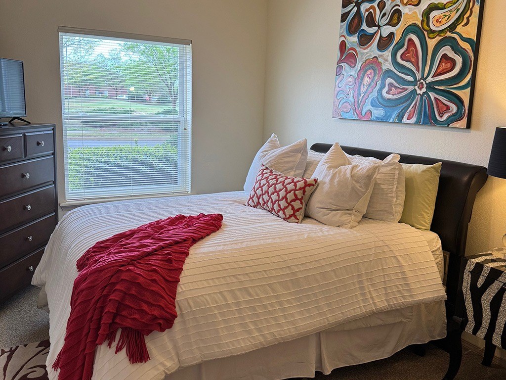 A bed with a red blanket and pillows in a room.