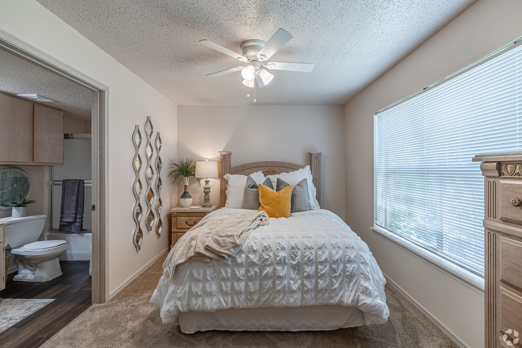 A bedroom with a bed, dresser, and ceiling fan.
