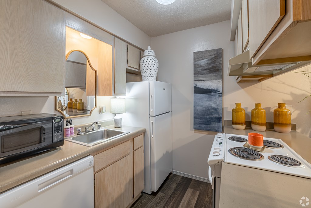 A kitchen with a white fridge, white stove, and white microwave.