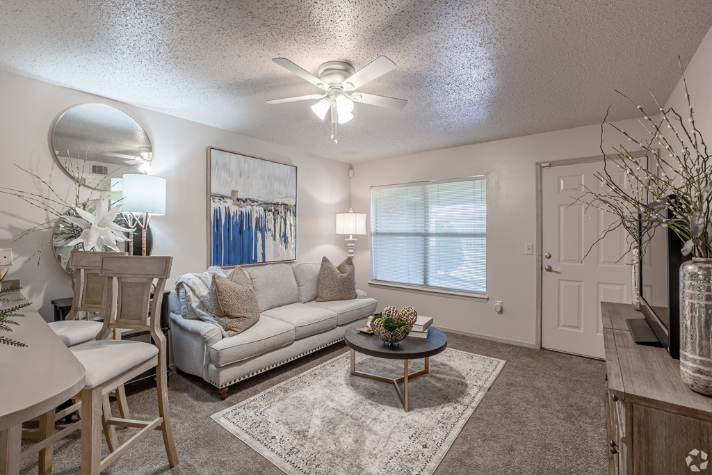 A living room with a white couch and a ceiling fan.