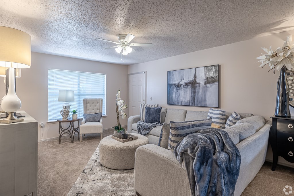 A living room with a couch, chair, and a table with a vase on it.