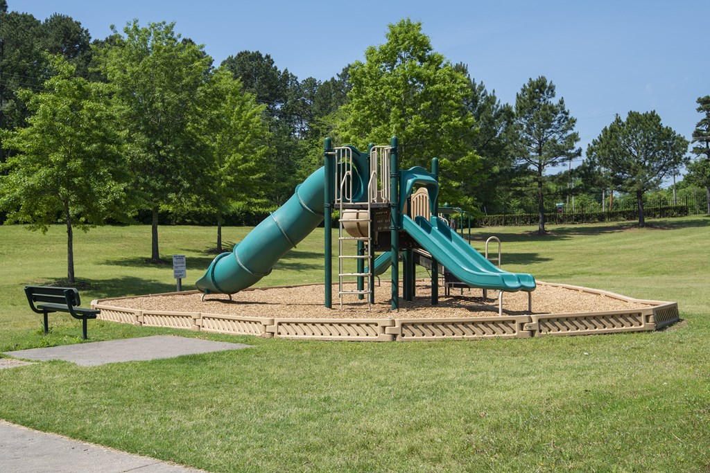 A playground with a green slide and a wooden platform.