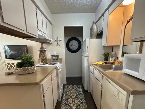 A kitchen with white appliances and a clock on the wall.