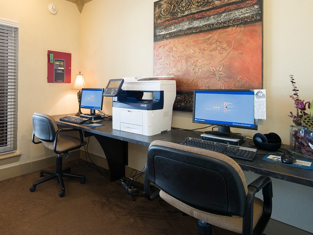 an office with two computers and a printer on a desk