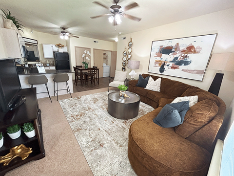 A living room with a brown couch and a rug.