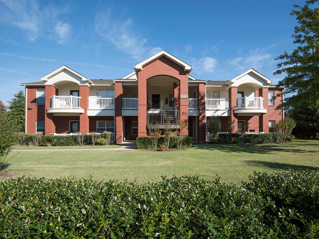an apartment building with a green lawn and a blue sky