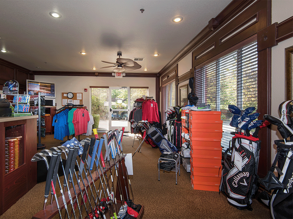a rack of golf clubs in a room with windows and a ceiling fan