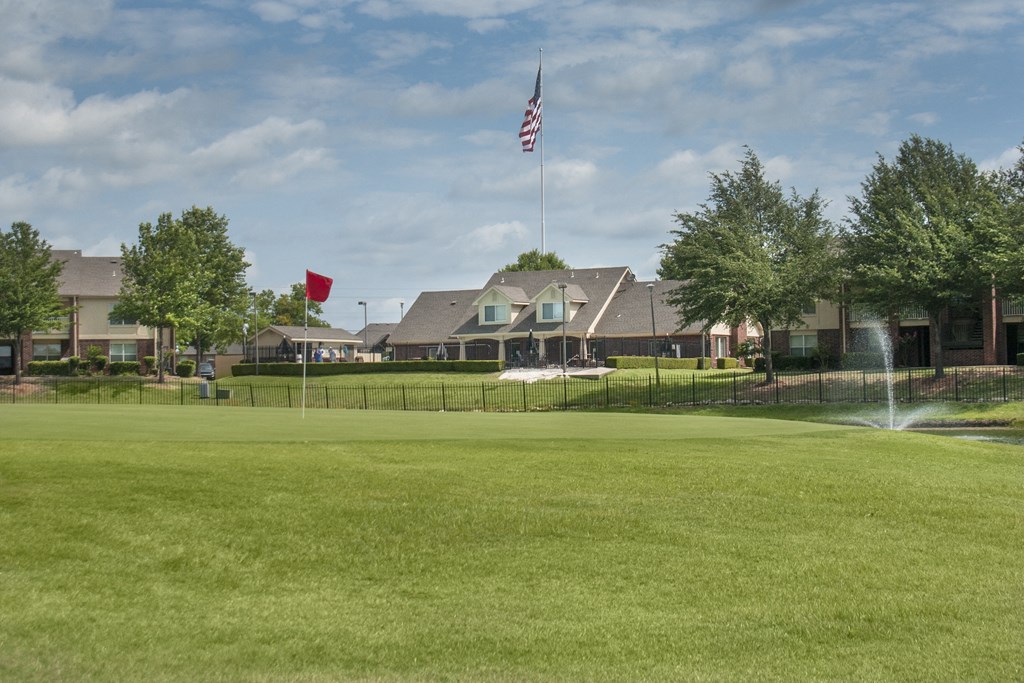 a large lawn in front of a the club house with a fountain
