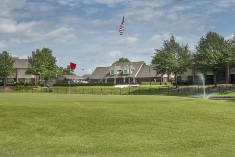 a large lawn in front of a the club house with a fountain