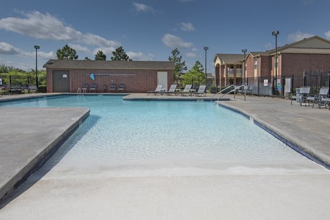 A swimming pool with a blue tinted water and a white sandy bottom.