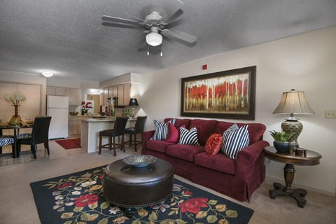 A living room with a red couch and a ceiling fan.