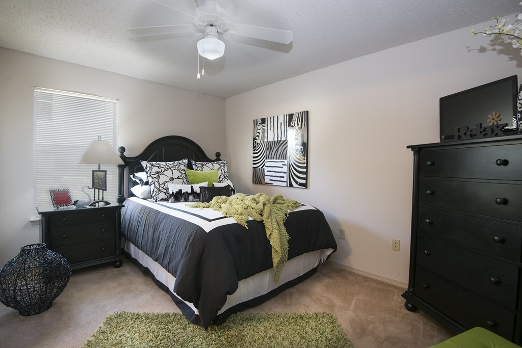 A bedroom with a bed, dresser, and ceiling fan.