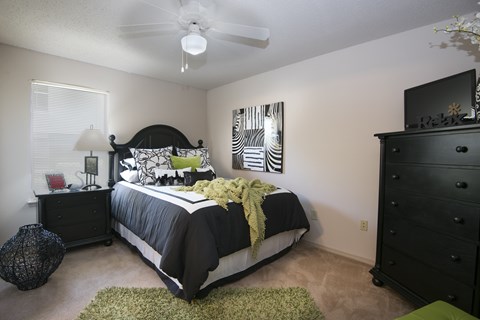 A bedroom with a bed, dresser, and ceiling fan.
