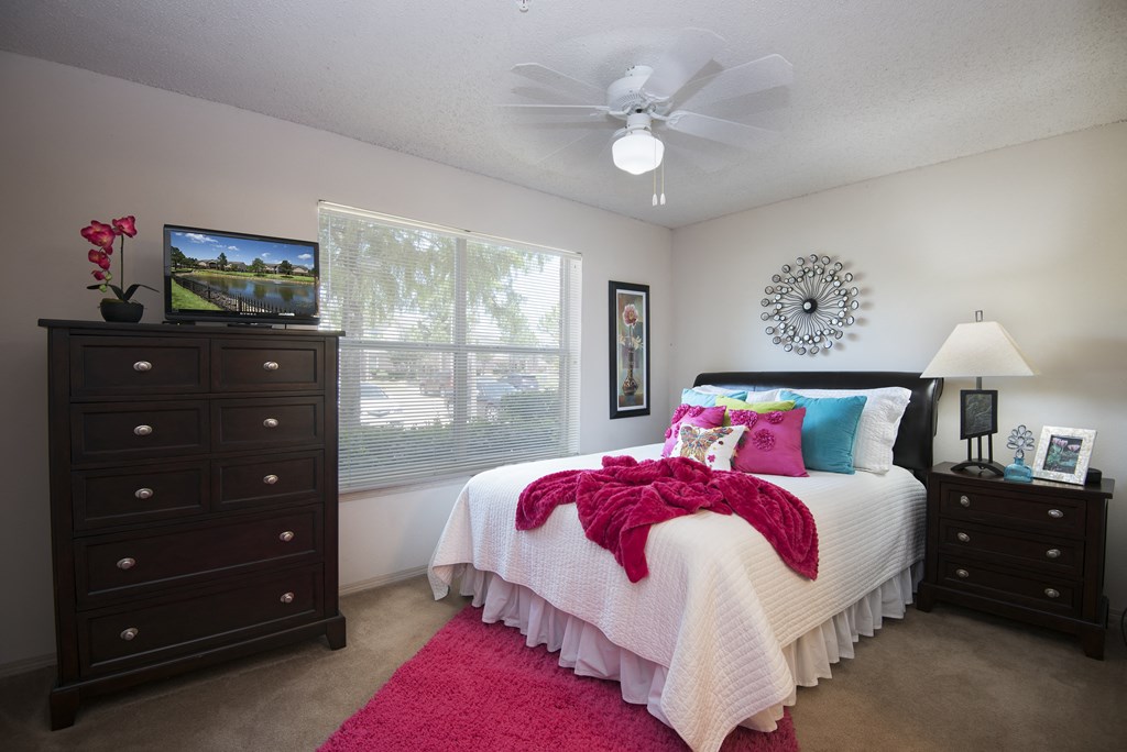 a bedroom with a bed, a dresser, and a ceiling fan