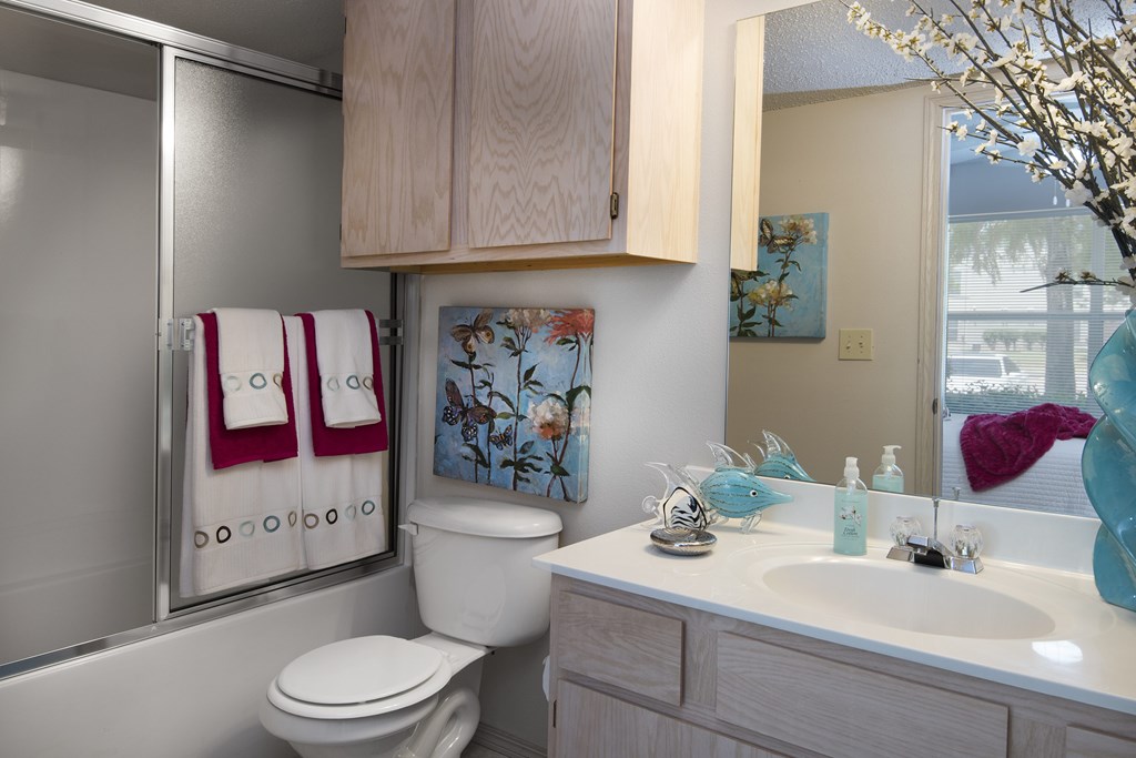 A bathroom with a toilet, sink, and a painting on the wall.