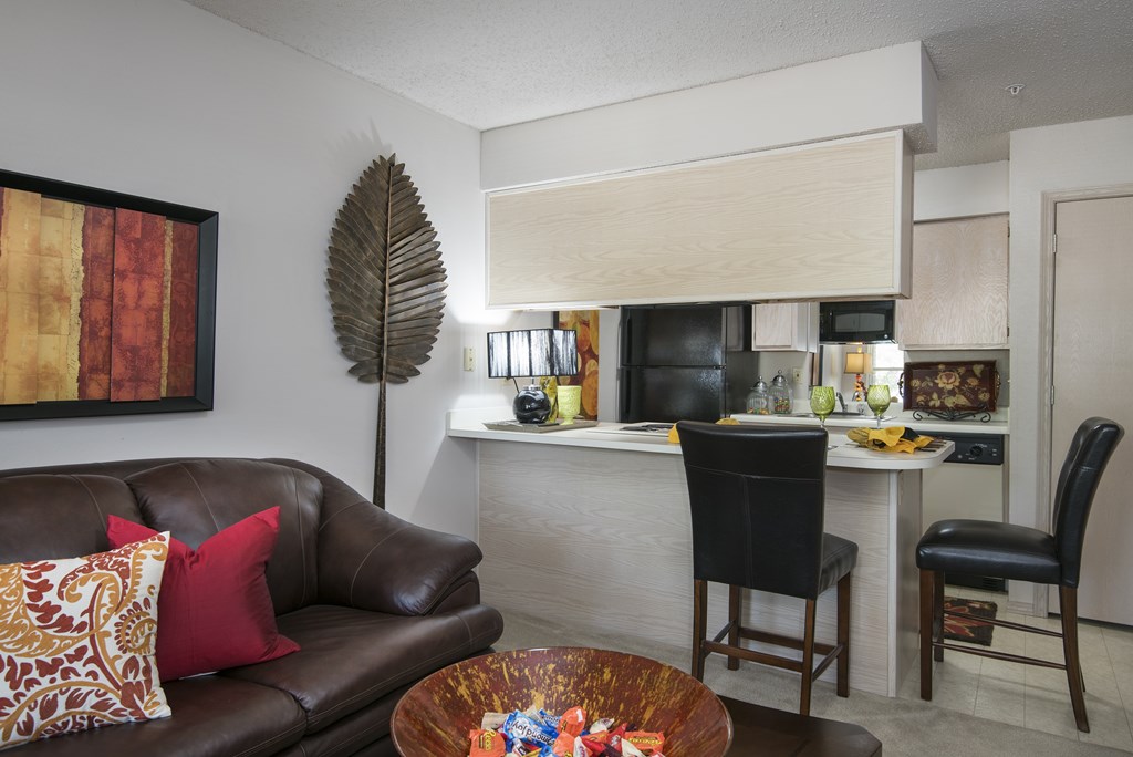 A brown leather couch with a red pillow and a brown wooden coffee table.