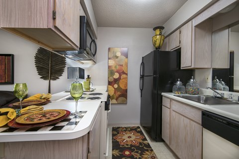 A kitchen with a black refrigerator and a table set for two.